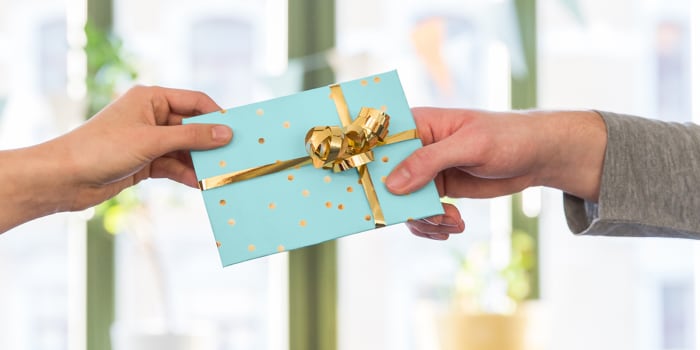 Une personne remet à une autre un chèque-cadeau emballé avec amour