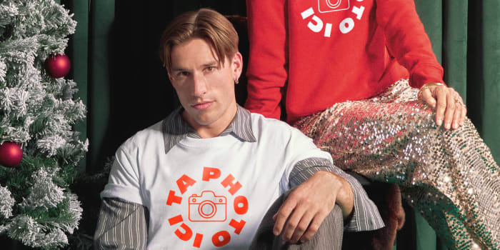 Homme et femme posent devant un sapin de Noël, portant des pulls avec l’inscription «Ta photo ici »