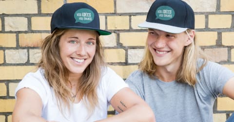 Devant un mur, un couple avec leurs tuques personnalisées